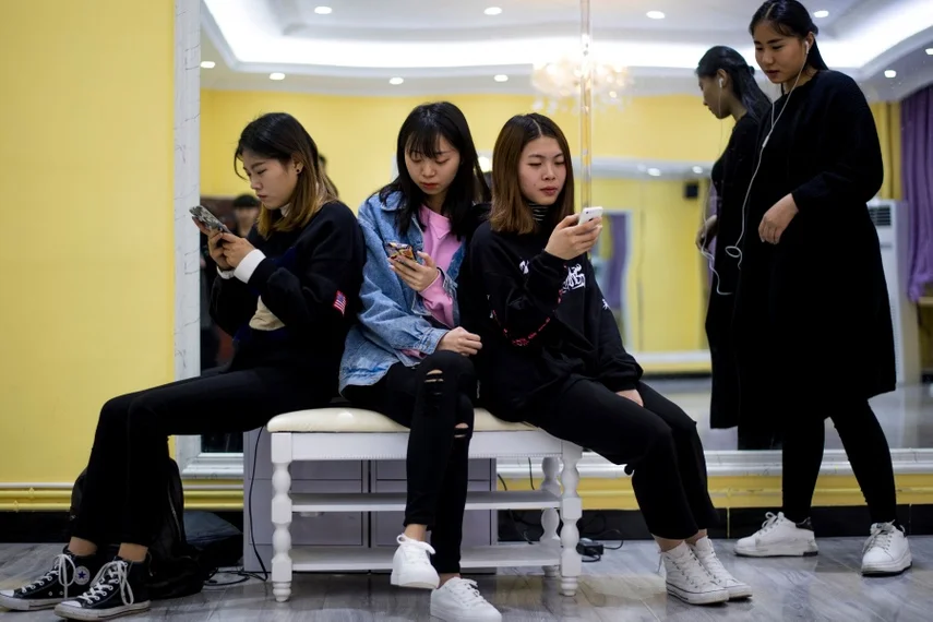 Chinese Gen Z teenagers using smartphones together illustrating the digital lifestyles of Chinese Gen Z consumers