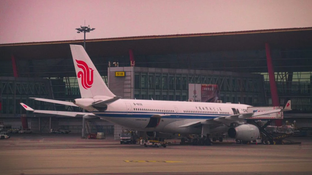 Air China passenger airplane parked at an airport gate in Beijing with terminal building in the background