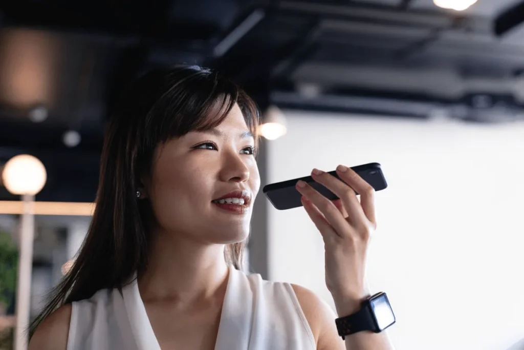 Woman using a smartphone for voice input in a modern office