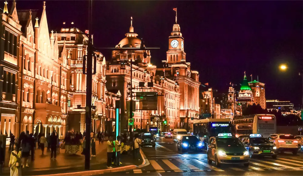 waterfront illuminated at night with traffic and pedestrians